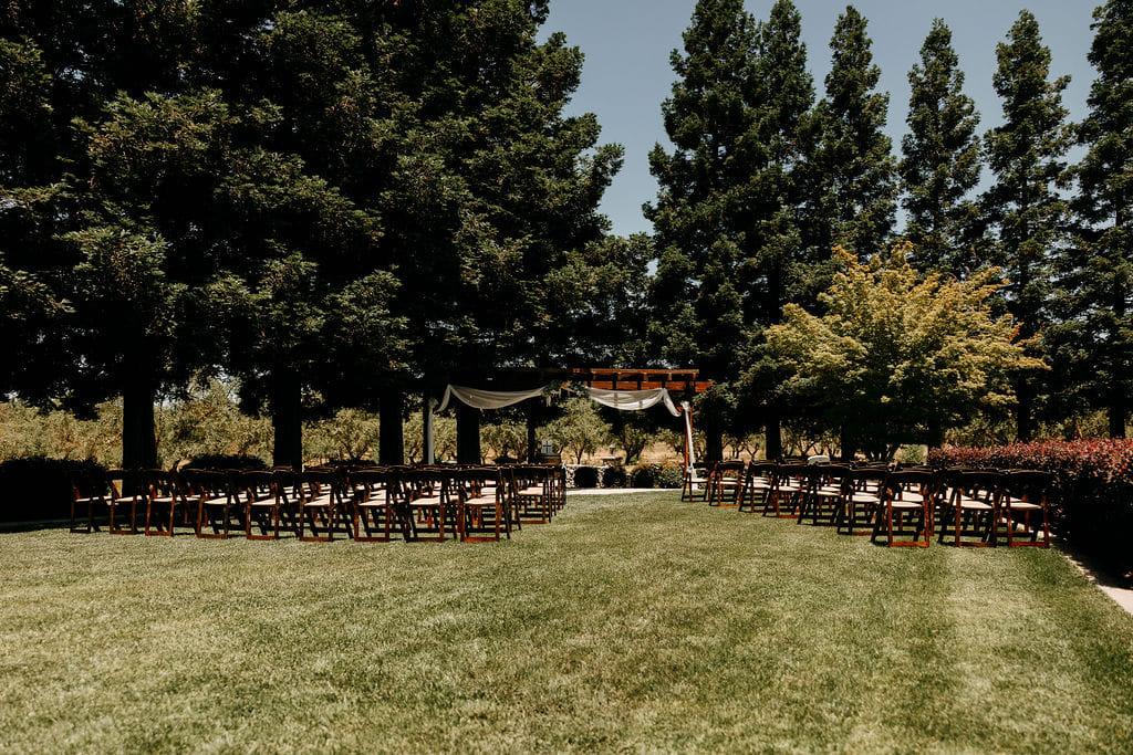 Ceremony seating facing the draped arbor beneath the redwoods