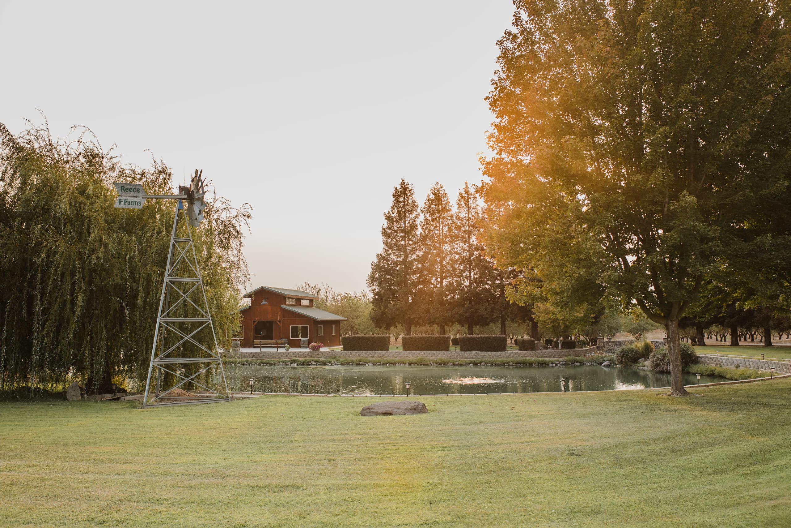 The open lawn at golden hour, windmill and barn across the water