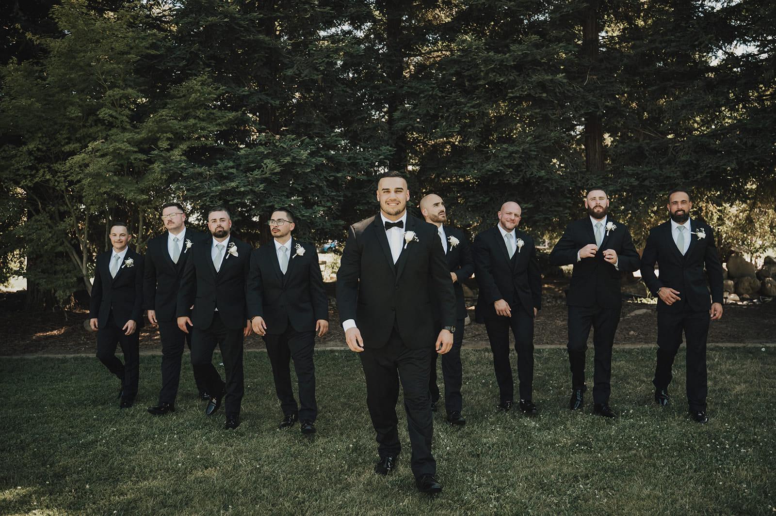 The groom and his groomsmen walking across the lawn