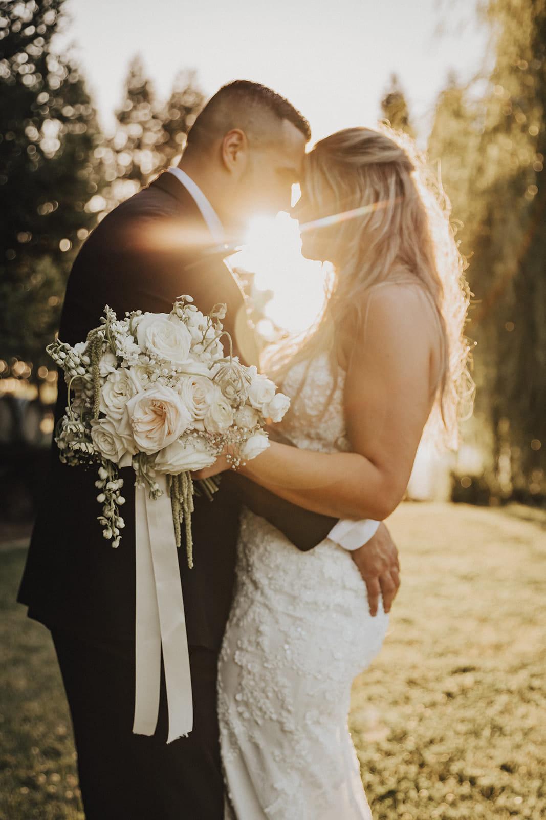 The couple leaning together with the sun bursting between them