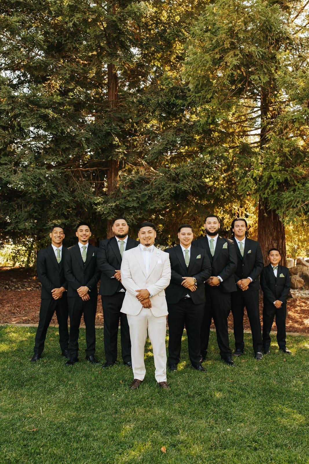 The groom in white with his groomsmen beneath the redwoods