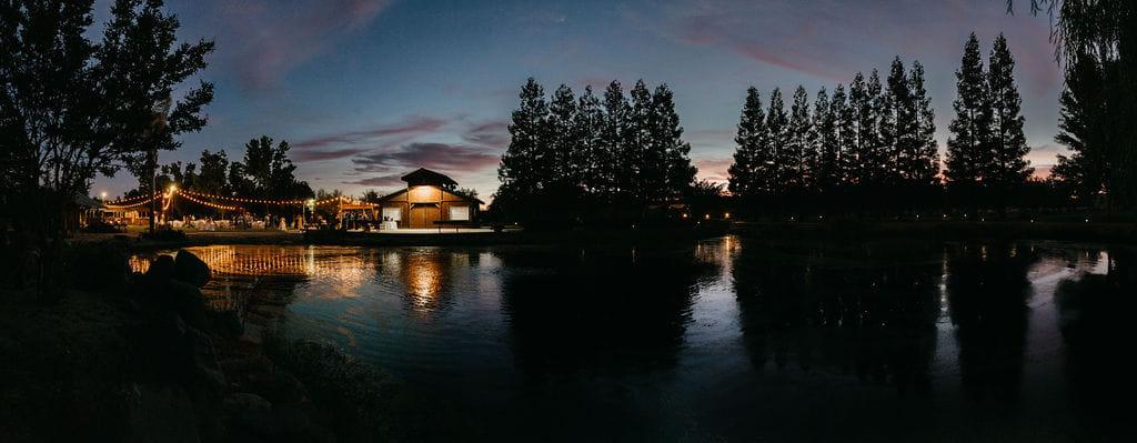 The grounds after dark, string lights reflected the length of the pond